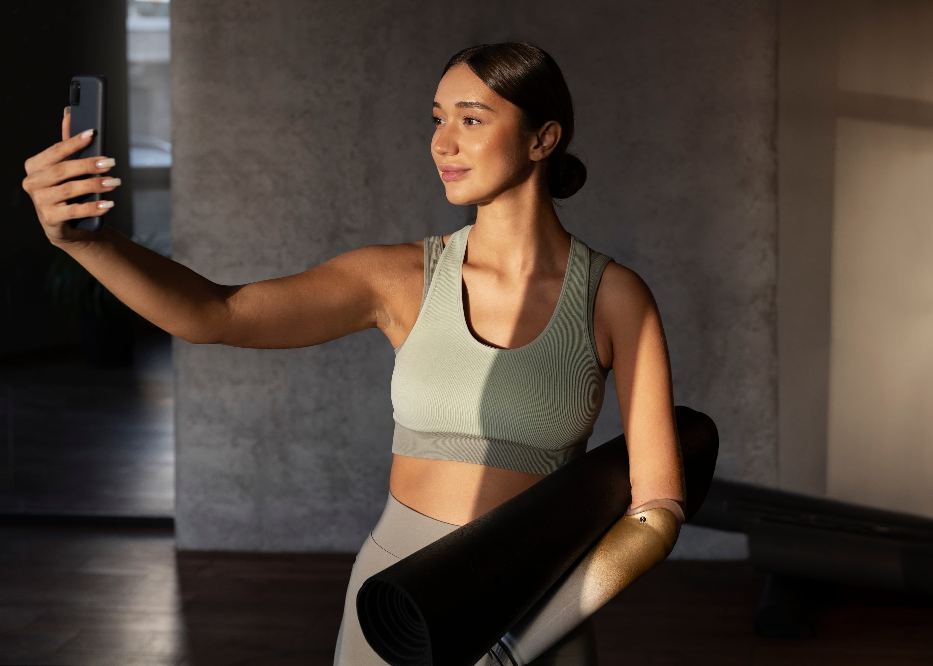 Mulher fazendo uma selfie segurando um tapete de yoga
