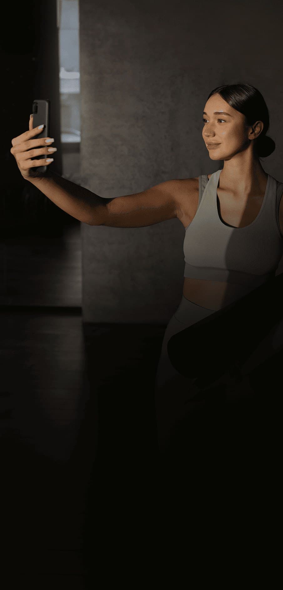 Mulher fazendo uma selfie segurando um tapete de yoga