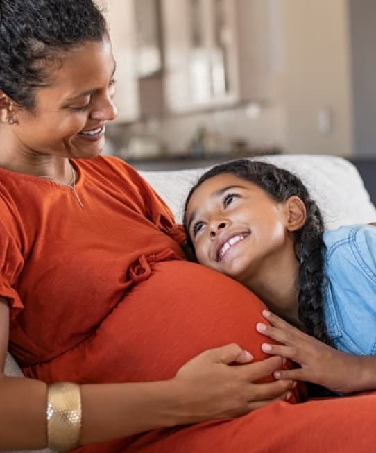 Gestante e filha deitadas no sofá