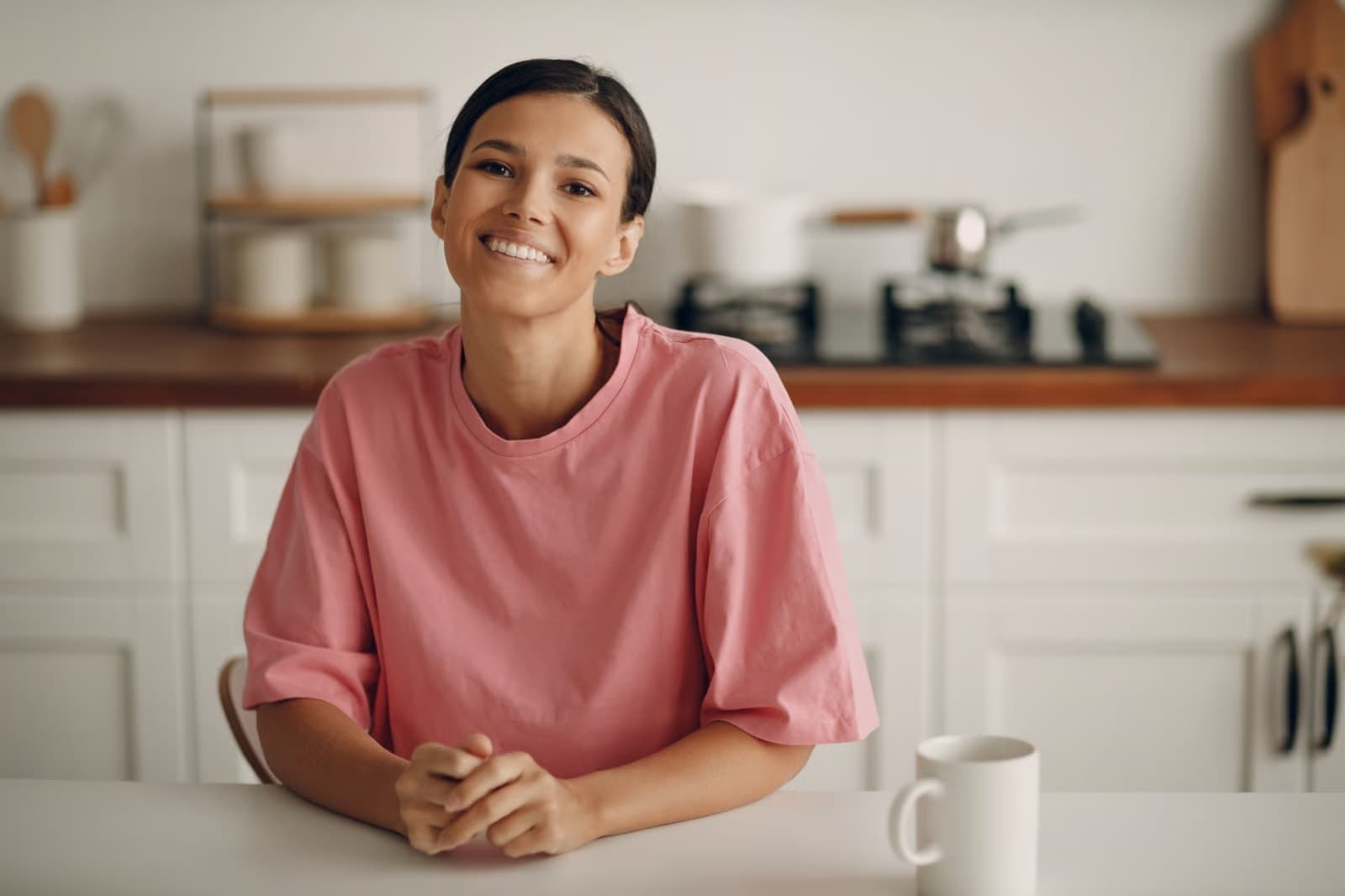 Mulher sorrindo apoiada na bancada da cozinha
