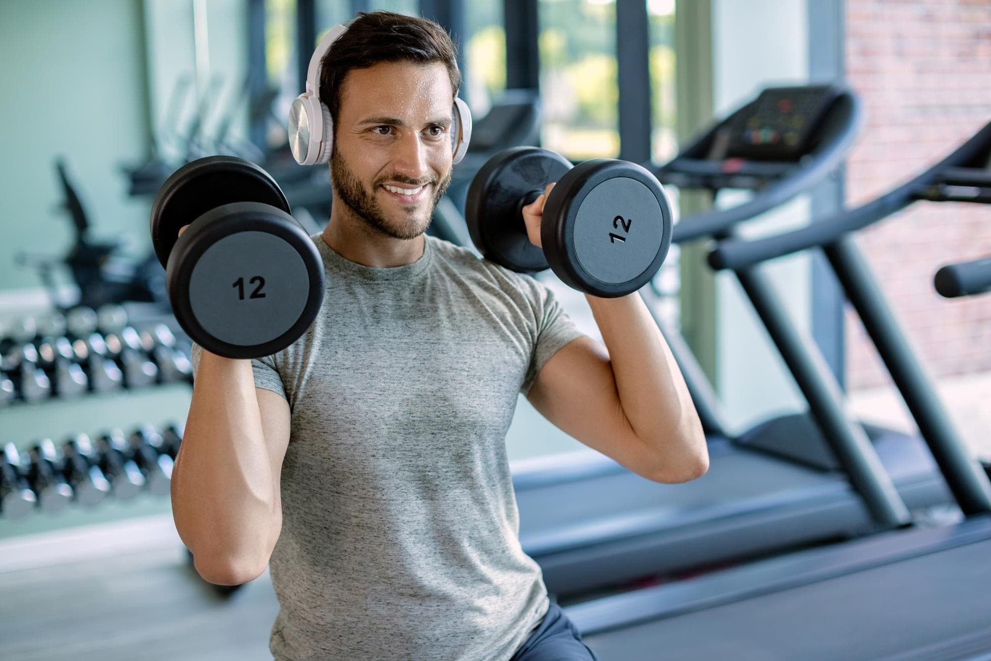 Homem treinando com halteres na academia