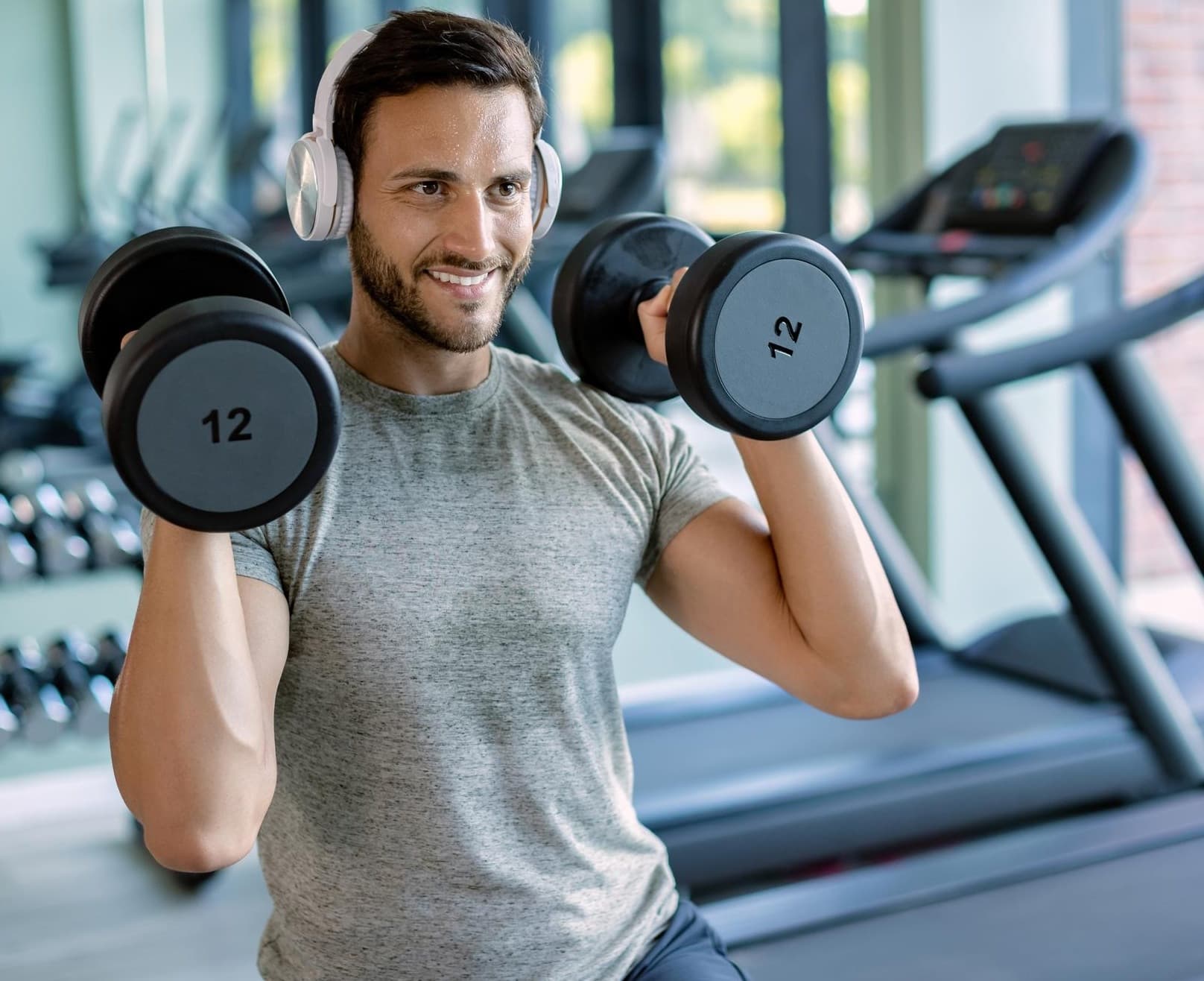 Homem treinando com halteres na academia