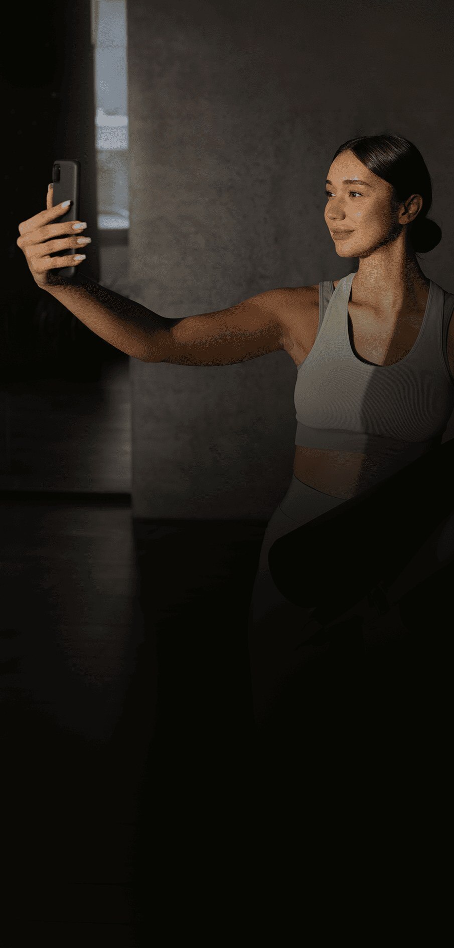 Mulher fazendo uma selfie segurando um tapete de yoga